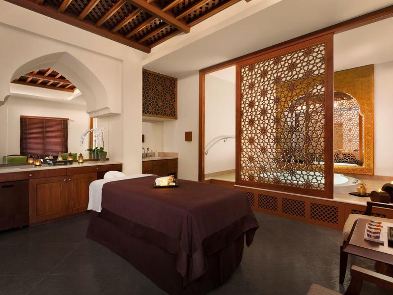 Salle de spa élégante avec table de soin, plafond en bois et écran décoratif.