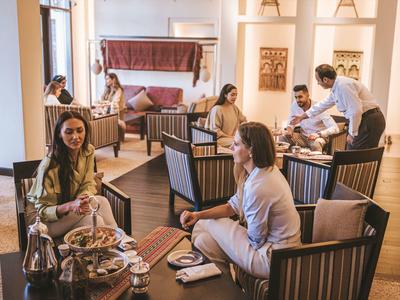 Hotel guests relax in a cozy lounge area with armchairs and tea service.