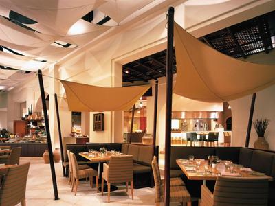 Modernes Restaurant mit bequemen Sesseln, hängenden Stoffen und gemütlicher Beleuchtung.