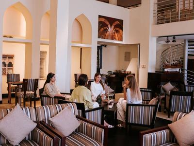 Innenbereich einer Hotel-Lounge mit Gästen und Komfortsesseln bei warmem Licht.