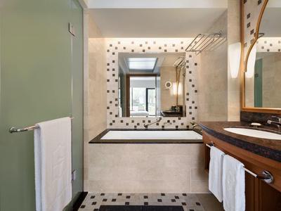 Modern bathroom with bathtub, large mirrors, and wooden furniture.