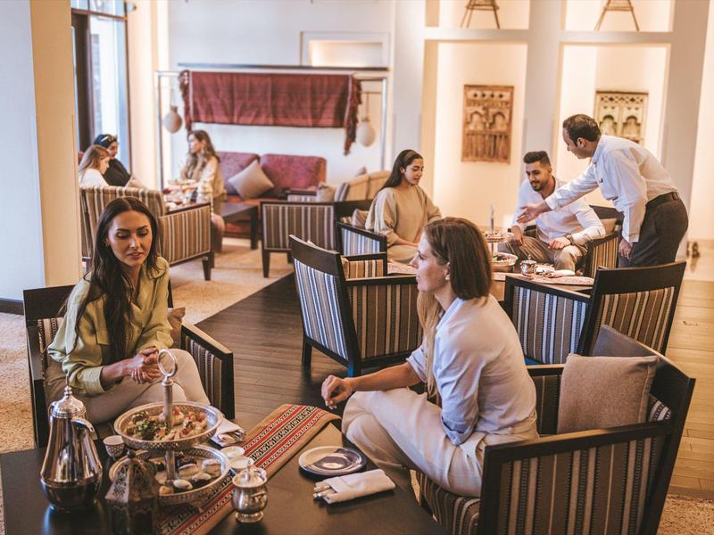 Hotel guests relax in a cozy lounge area with armchairs and tea service.