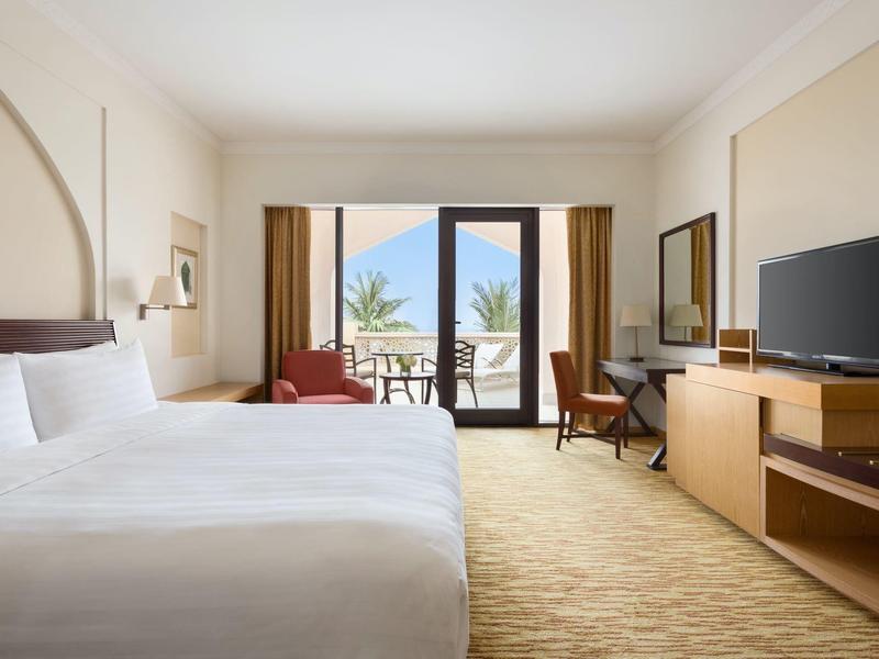 Bright hotel room with two beds, balcony, and TV.