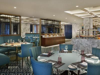 Restaurante moderno con sillas azules, mesas redondas y ambiente elegante.