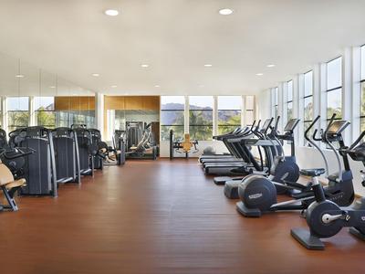 Großer, heller Fitnessraum mit Trainingsgeräten und Aussicht auf die Natur.