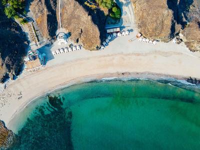 Luftaufnahme eines halbkreisförmigen Strandes mit klarem grünen Wasser und felsigen Klippen