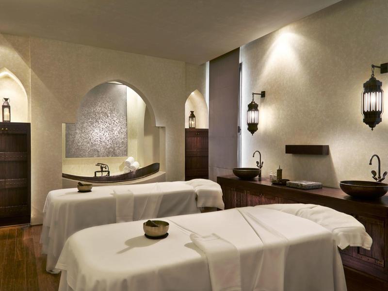 Sala de spa tranquila con dos camillas de masaje, faroles y ambiente cálido.