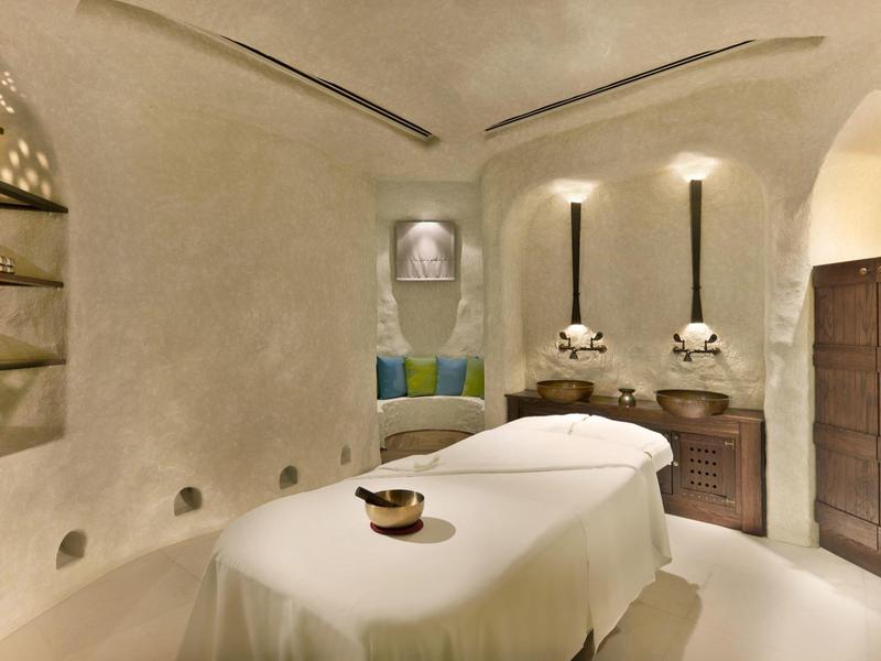 Sala de bienestar acogedora con camilla de masaje, paredes suaves y ambiente relajante.