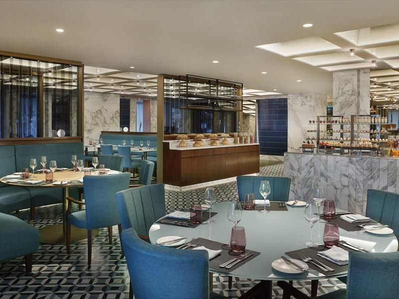 Restaurante moderno con sillas azules, mesas redondas y ambiente elegante.