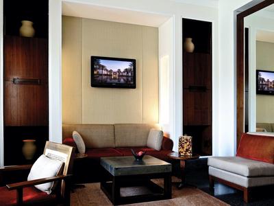 Moderně zařízený obývací pokoj s pohovkou, křesly a televizí na zdi.