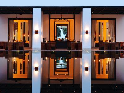 Symetrický pohled na osvětlený hotel s odrazy ve vodě za soumraku.