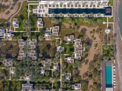 Letecký pohled na hotel u pláže s bazénem, zelenými oblastmi a stezkami v blízkosti