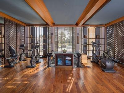 Modern gym with wooden floor and equipment next to large windows
