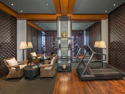 Modern fitness room with treadmill and cozy seating areas featuring dark wood design.
