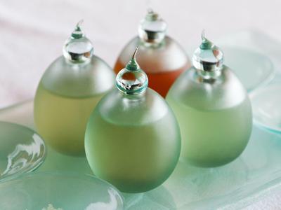Čtyři dekorativní malé skleněné lahve s různými kapalinami na tácu.