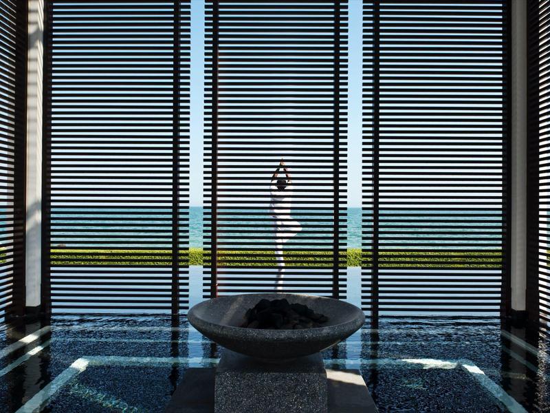 Moderní místnost se širokými okny s výhledem na moře, uprostřed je fontána.