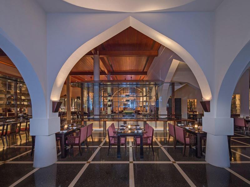 Elegantní hotelový lounge s oblouky, dřevěným nábytkem a teplým osvětlením.