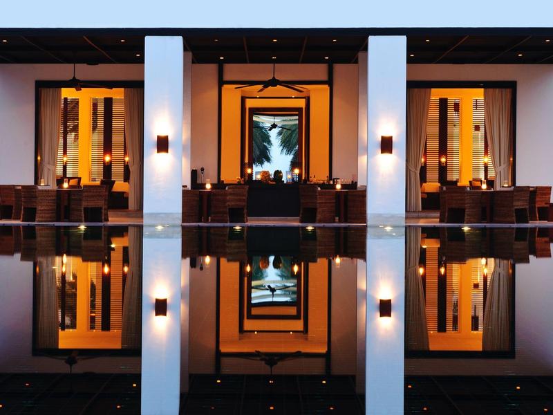 Symetrický pohled na osvětlený hotel s odrazy ve vodě za soumraku.