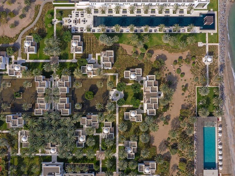 Letecký pohled na hotel u pláže s bazénem, zelenými oblastmi a stezkami v blízkosti