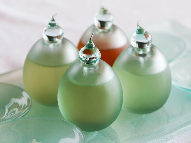 Čtyři dekorativní malé skleněné lahve s různými kapalinami na tácu.