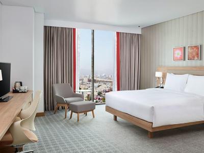 Camera d'hotel luminosa con grande finestra e vista sulla città.