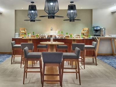 Moderner Frühstücksbereich mit einer langen Tafel, Stühlen und Buffetstationen in warmem Licht.