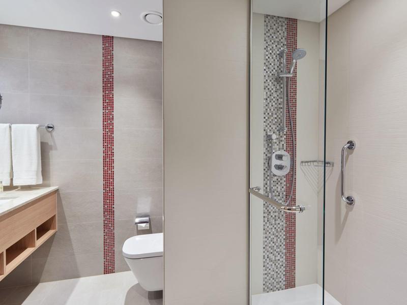 Bagno moderno in hotel con doccia, WC e lavabo con asciugamani.