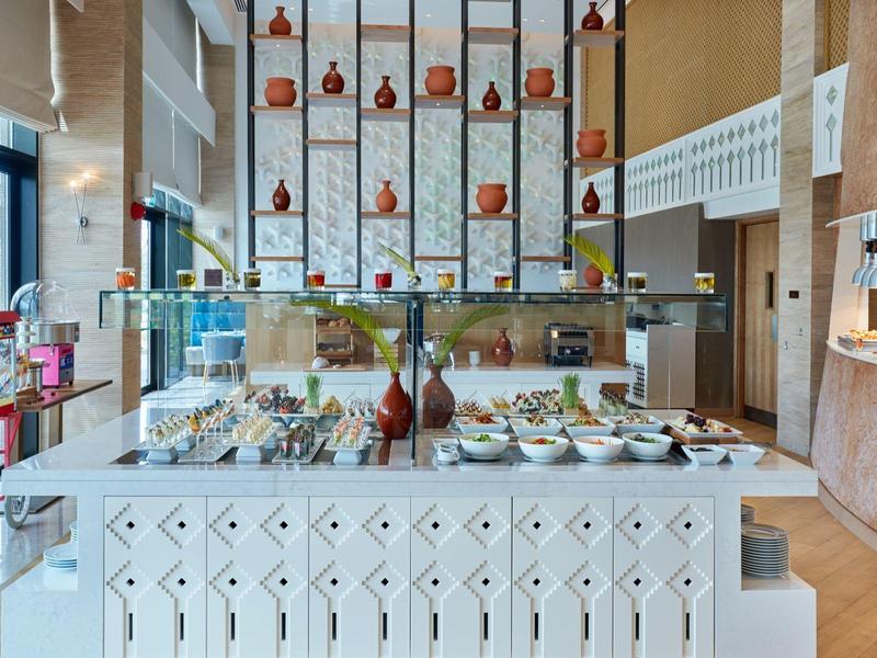 Ristorante d'hotel moderno con buffet luminoso e selezione di cibi e bevande.