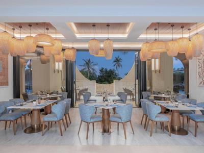Heller, moderner Speiseraum mit blauen Stühlen und Hängeleuchten, Terrasse mit Palmen im Hintergrund
