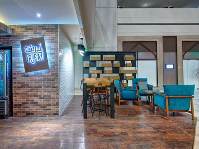 Gemütlicher Sitzbereich mit blauen Sesseln und Holztisch in modernem Hotelambiente.