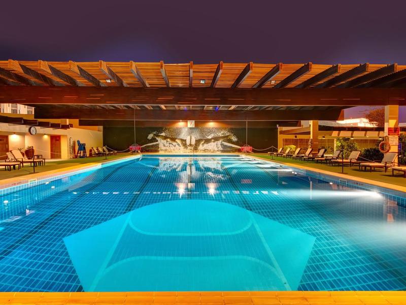 Piscine illuminée avec pergola en bois dans un hôtel la nuit