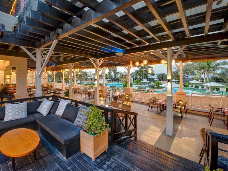 Salon couvert avec espace de sièges donnant sur la piscine d'un hôtel.