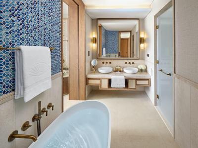 Salle de bain moderne avec baignoire îlot, mur à motif bleu et doubles lavabos.