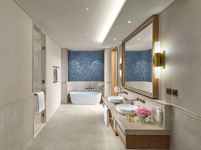 Salle de bain moderne avec baignoire autoportante, grand miroir et deux lavabos.