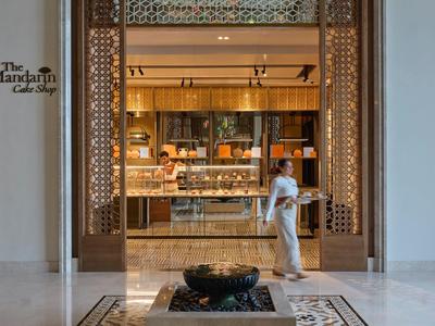Entrée élégante dans le hall d'hôtel avec des panneaux en bois ornés et une femme en tenue blanche.