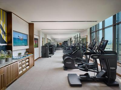 Moderne Fitnessstudio mit Trainingsgeräten und großer Fensterfront mit Stadtblick.