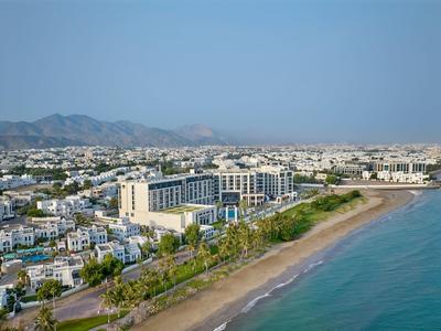 Vue panoramique d'un grand hôtel de plage avec des montagnes en arrière-plan.