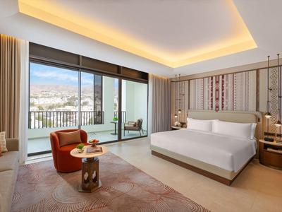 Chambre d'hôtel moderne avec grandes baies vitrées, terrasse et vue dégagée sur les montagnes.