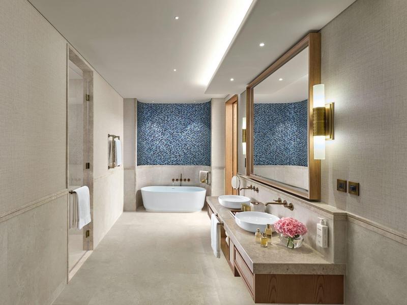 Salle de bain moderne avec baignoire autoportante, grand miroir et deux lavabos.