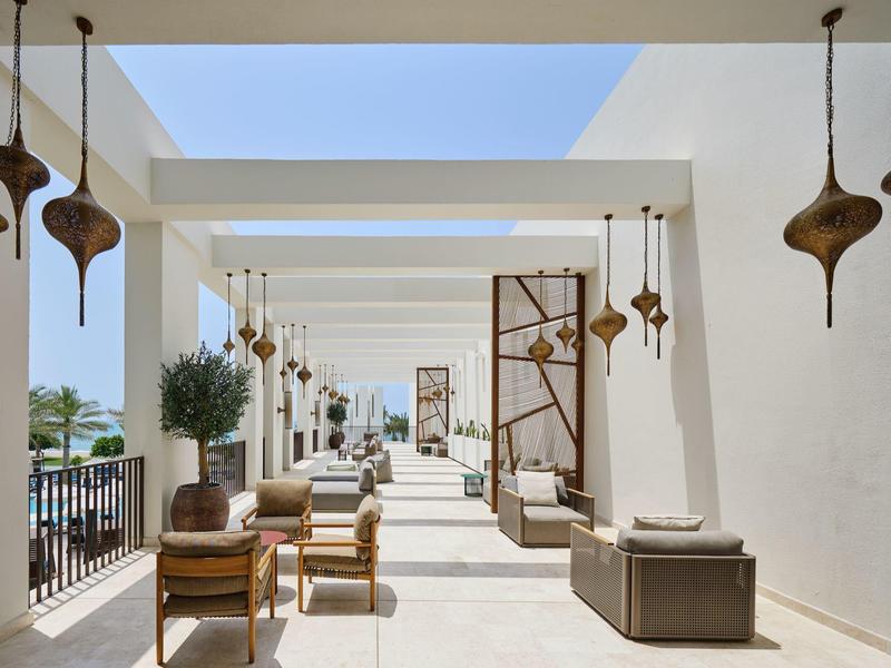 Espace extérieur moderne avec sièges et lampes suspendues sous un ciel ouvert.