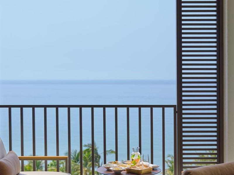 Balcon avec sièges et table, vue sur la mer et ciel clair