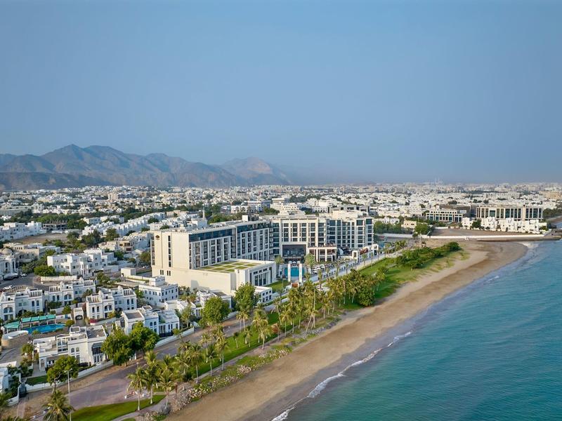 Vue panoramique d'un grand hôtel de plage avec des montagnes en arrière-plan.