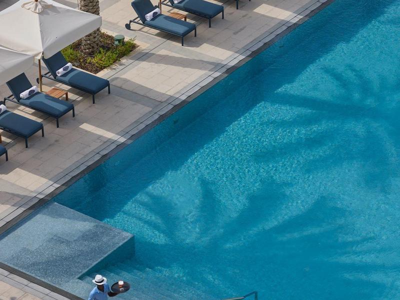 Vue d'une piscine d'hôtel avec chaises longues et parasols sur un côté.