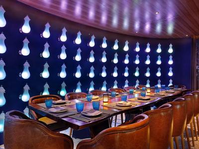 Elegantní jídelní prostor s modrým nástěnným osvětlením a dřevěným stolem v hotelu.