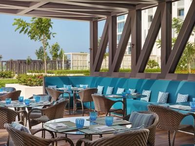 Espace extérieur moderne avec des bancs rembourrés bleus et plusieurs tables dressées.