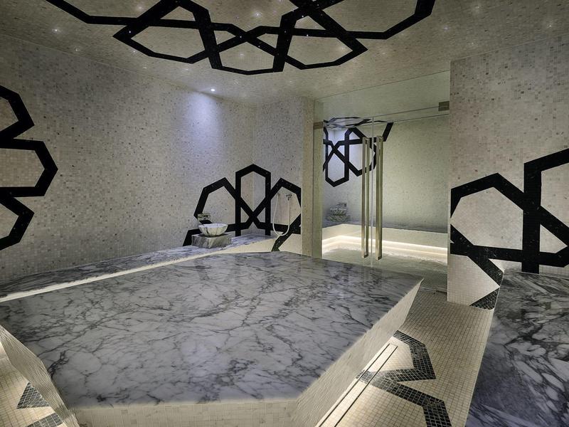 Moderní wellness místnost s mramorovou vanou a dekorativními černo-bílými vzory na stěnách.