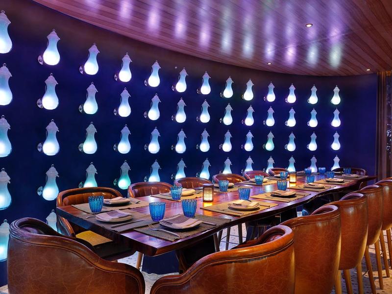 Elegantní jídelní prostor s modrým nástěnným osvětlením a dřevěným stolem v hotelu.