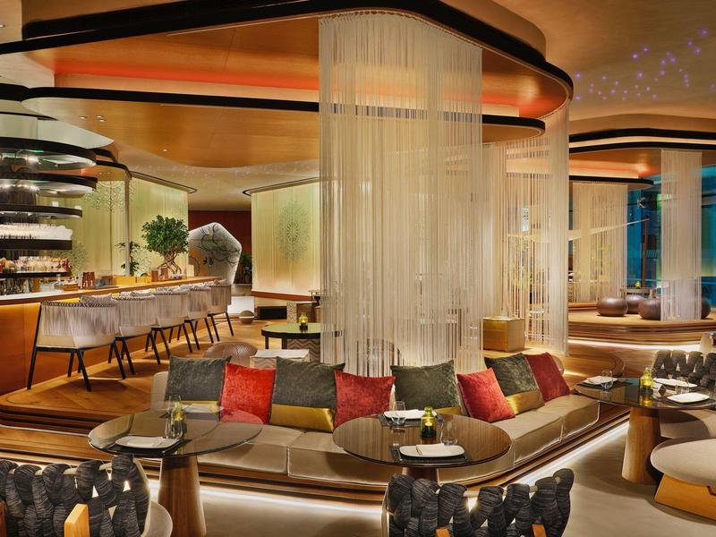 Moderní hotelová lounge s zakřiveným posezením a barevnými polštáři.