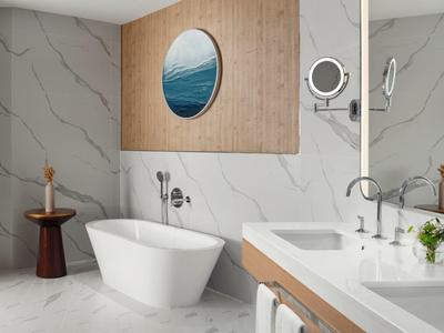 Moderní koupelna s volně stojící vanou, dvojnásobným umyvadlem a námořnickou nástěnnou dekorací.