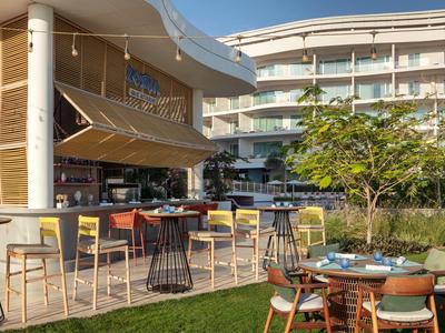 Moderní venkovní prostor hotelu s barem a posezením za denního světla.